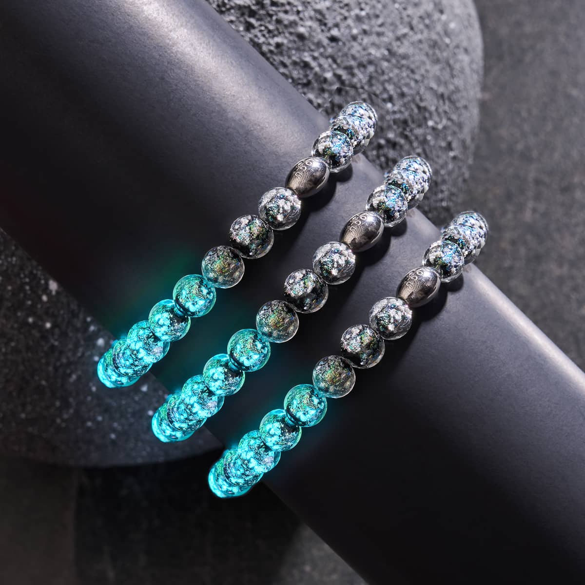 Neon Black Firework Glass Bracelets with glowing blue beads and .925 sterling silver clasps displayed on black surface by NOGU